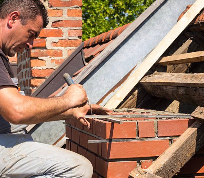 Technician rebuilding a brick chimney